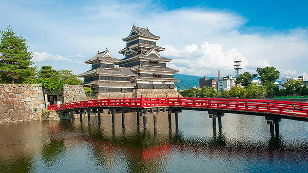 Matsumoto Castle with vibrant red bridge in summer