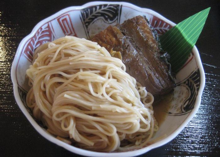 A bowl of yakisaba somen, with a portion of mackerel on a bed of noodles