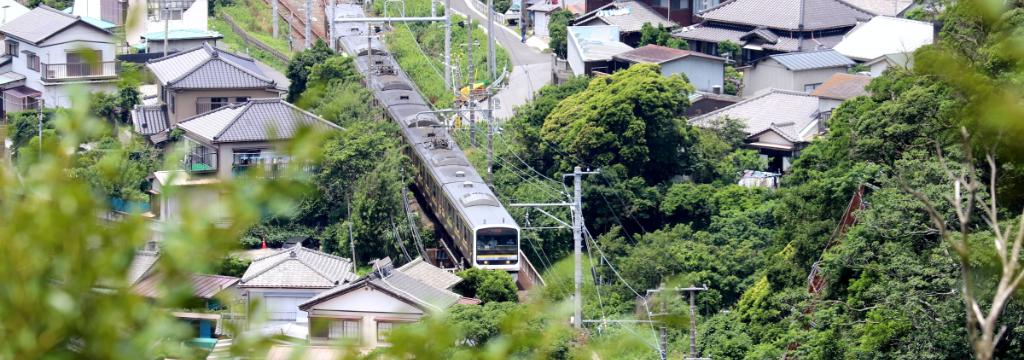 Scenic train passing through a lush suburban Japanese neighborhood