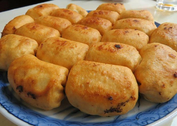 Many crispy fried circular golden-brown gyoza potstickers on blue plate