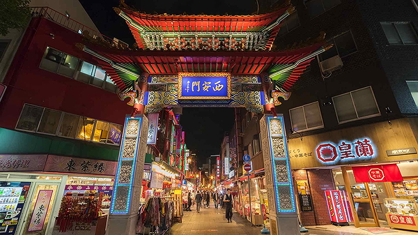 Illuminated Chinatown gate in lively city night scene