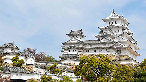 Himeji Castle surrounded by lush greenery under a clear sky