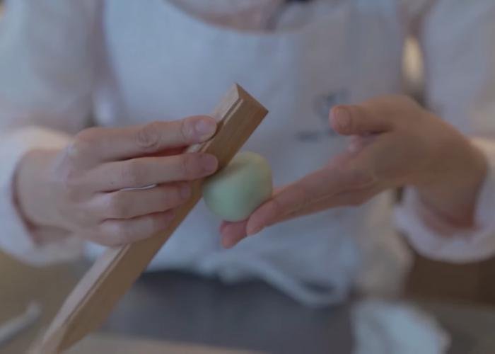 Hand using wooden stick tool to make indent in japanese wagashi dough