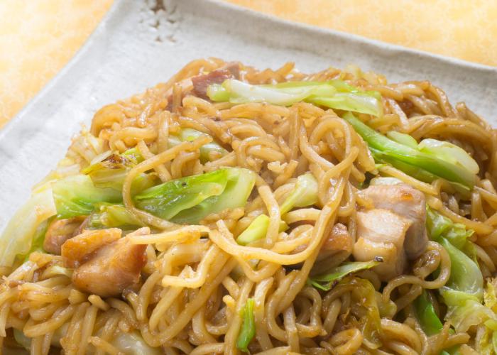 A close-up of yakisoba, showing the saucy stir-fried noodles, meats and veggies.