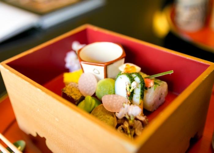 A close-up shot of delicate and colourful kaiseki cuisine in a wooden box