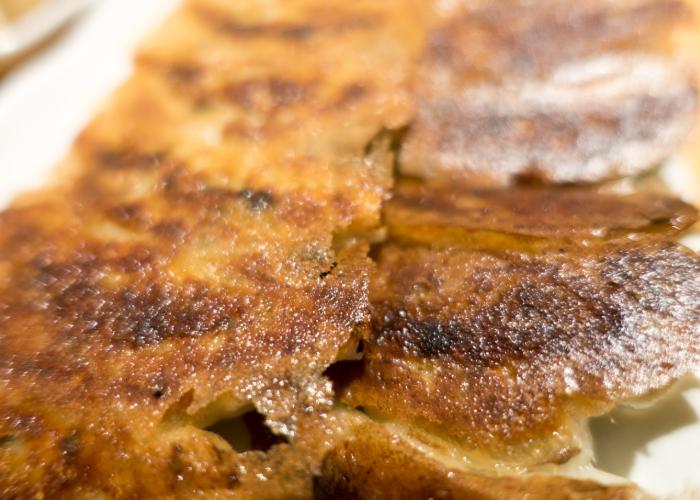 A close-up image of the crispy top of a row of gyoza dumplings