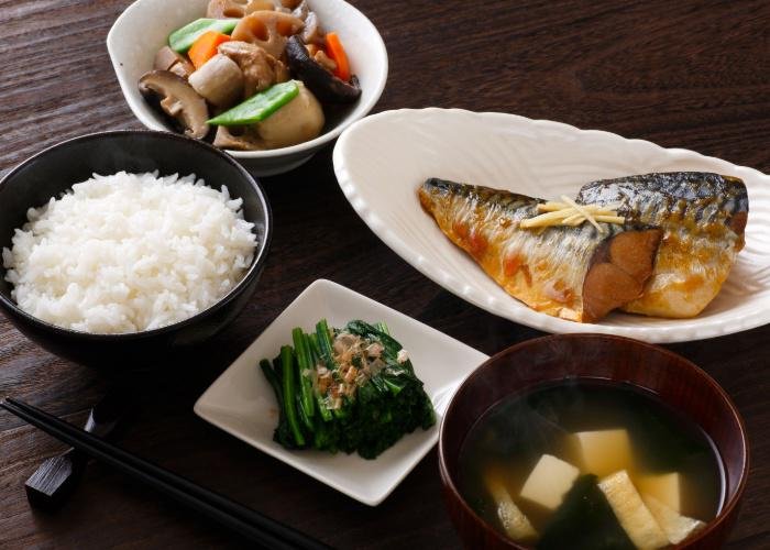 Japanese style breakfast with grilled fish, miso soup, rice, and veggie sides