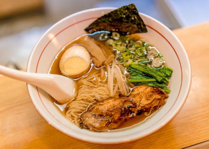 Bowl of Kyoto ramen with light colored broth, thin noodles, a large piece of meat