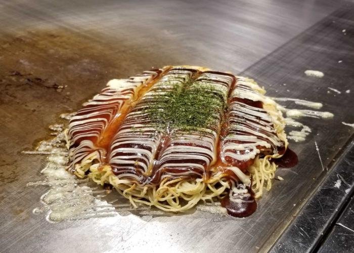 Classic Hiroshima-style okonomiyaki topped with Otafuku sauce, mayo, and a beautiful design