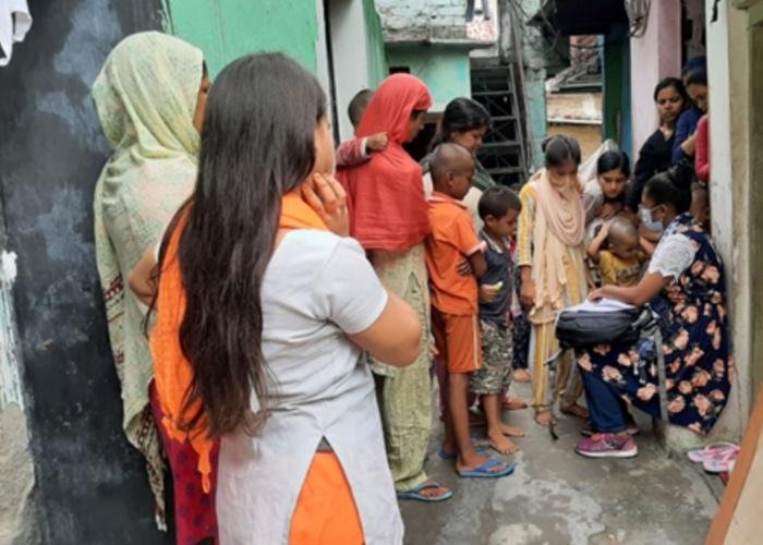 Schoolchildren in India gather around women who check their schoolwork