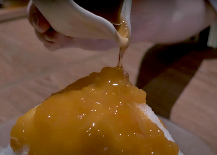 Syrup being poured onto a mound of shaved ice