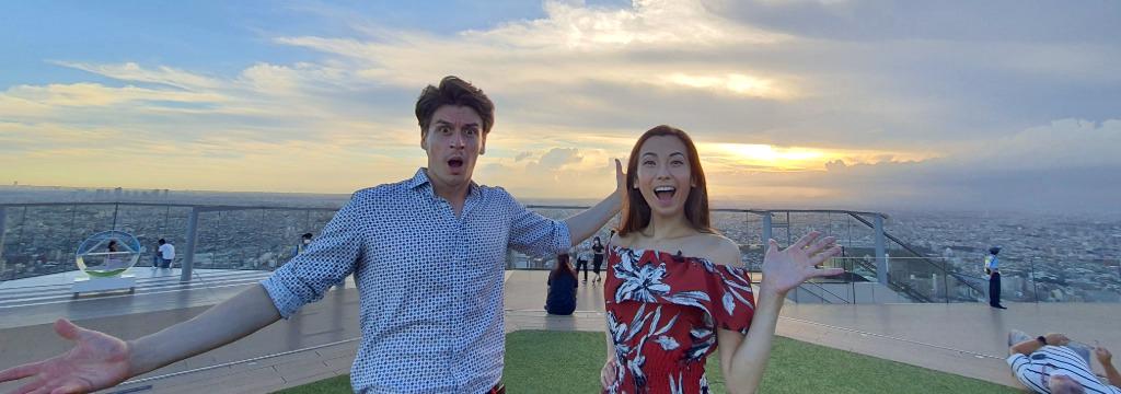 Excited couple enjoying city skyline at sunset on rooftop