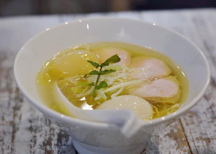 Bowl of peach ramen in Tokyo with a peach slice floating in the broth
