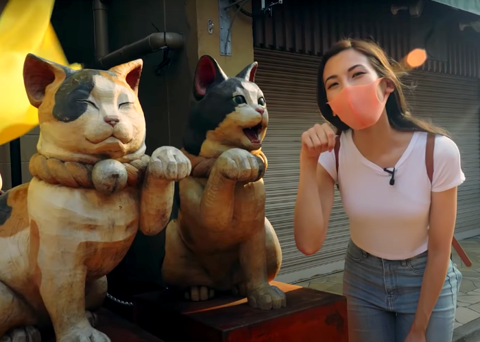Shizuka Anderson poses next to cat statues in Yanaka Ginza