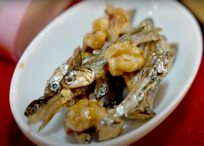 Close-up of a small white bowl of  tazukari (candied sardines)