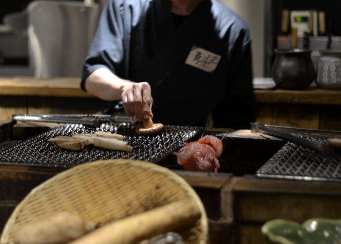 Cook at work at Robatasho in Shinjuku, grilling a Shiitake mushroom