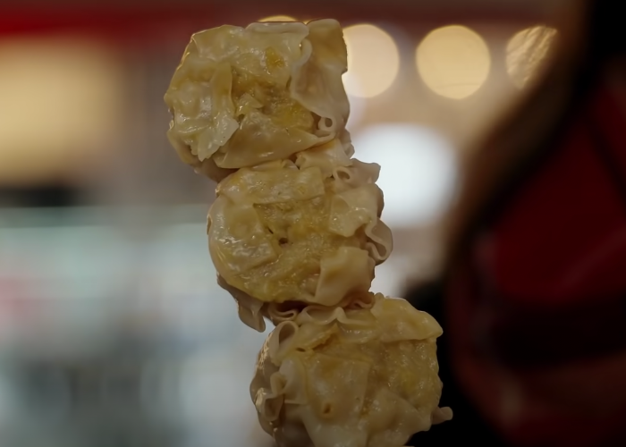Close up image of three shrimp shumai dumplings on a stick