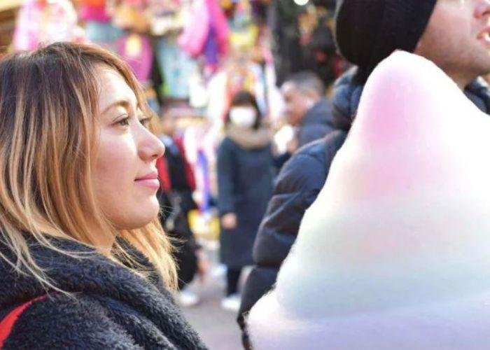Woman with brown dyed hair looking at puffy pastel rainbow cotton candy