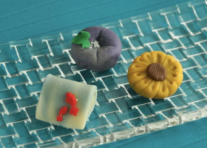Three different colorful wagashi sweets on a blue background