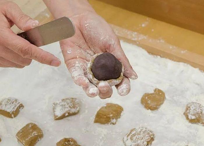 Close up of someone with floury hands halfway through making manju