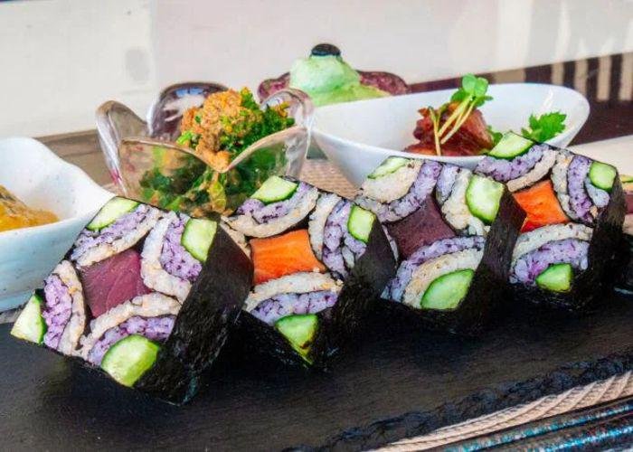 A close up shot of sushi rolls with a mosaic design on a black board
