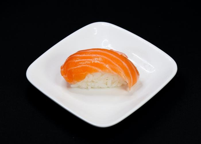 Atlantic Salmon nigiri sushi on a white plate with a black background