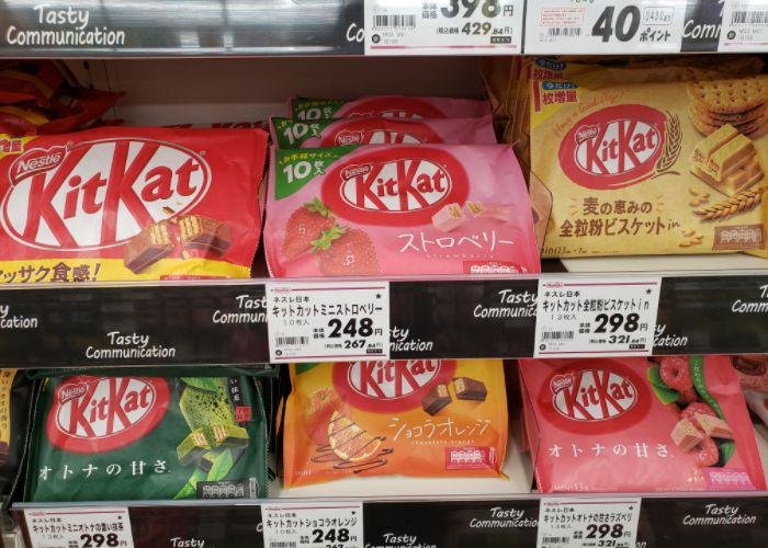 Packages of chocolate, matcha, orange, raspberry, & strawberry Kit Kats on grocery shelves