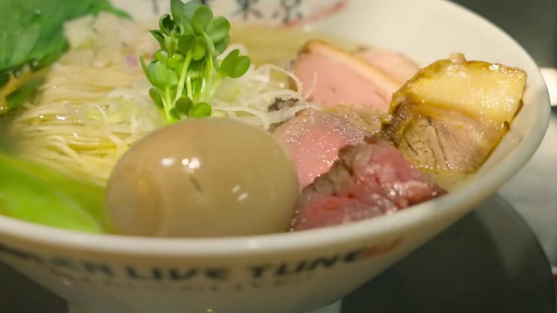 Delicious bowl of ramen with eggs and meat garnished with greens