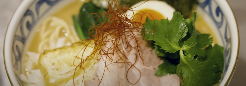 Delicious bowl of ramen with egg, noodles, and herbs