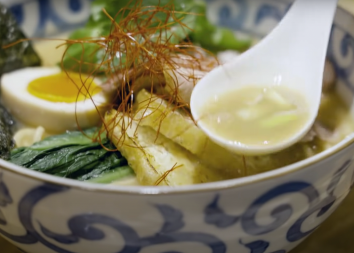 Close up image of a bowl of ramen with a spoon holding some broth