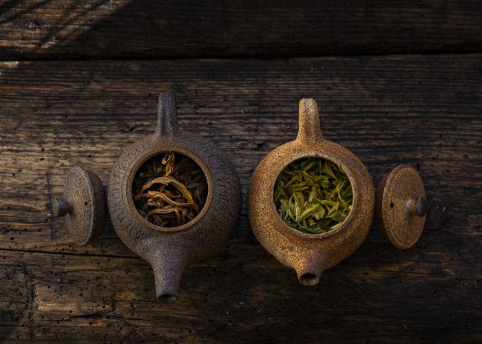 An overhead shot of two traditional teapots filled with tea leaves