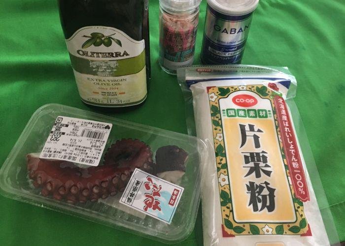 Tako karaage ingredients including boiled octopus tentacles and potato starch, laid on on a green tablecloth