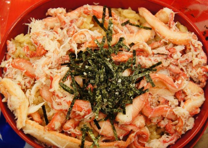 A close up image of crab meat mixed with rice and topped with dried seaweed