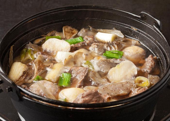 An iron pot dish full of thinly sliced meat and vegetables in soup, a Yamagata specialty dish