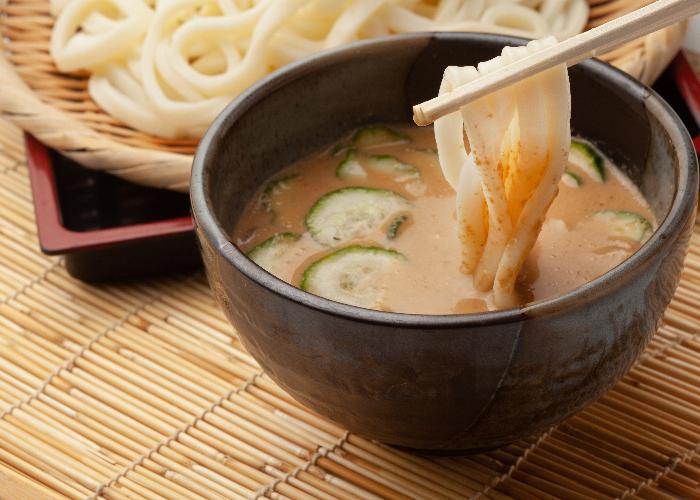 Hiyajiru udon, a dipping sauce with cold cucumbers and a plate of udon noodles in the background