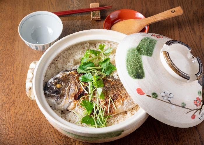 A small nabe pot filled with rice and topped with a sea bream