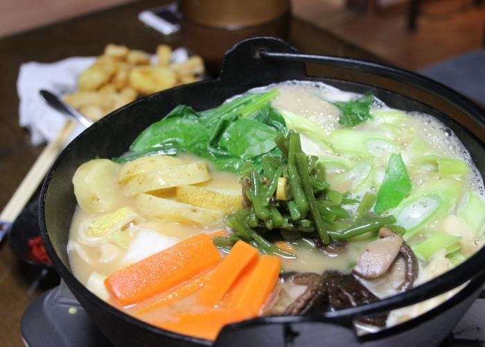 Hoto noodles cooking in an iron pot with carrots and other veggies