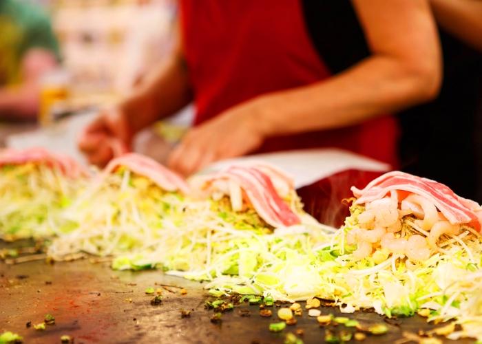 Hiroshima okonomiyaki being made on a teppan griddle