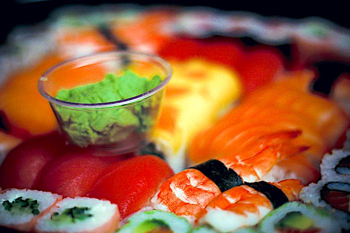 Pile of sushi with a small bowl of wasabi sitting on top of it