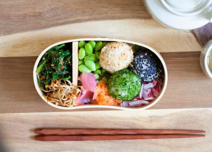 Colorful vegetable bento box filled with rice balls and veggies