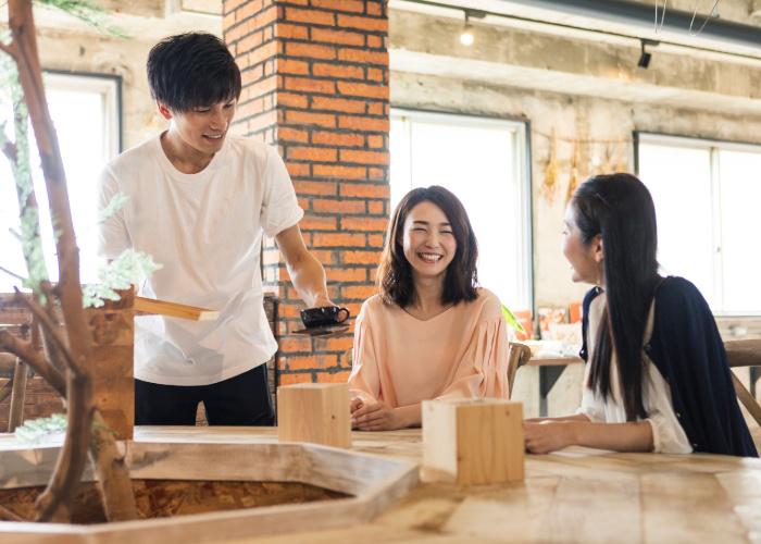 Cafe staff serving two customers coffee