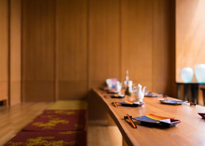 Japanese restaurant interior with cushioned floor seating and a table set with chopsticks and plates