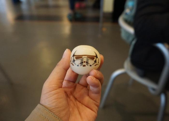 A hand holding a white mochi rice cake with a Storm Trooper helmet stamped on it