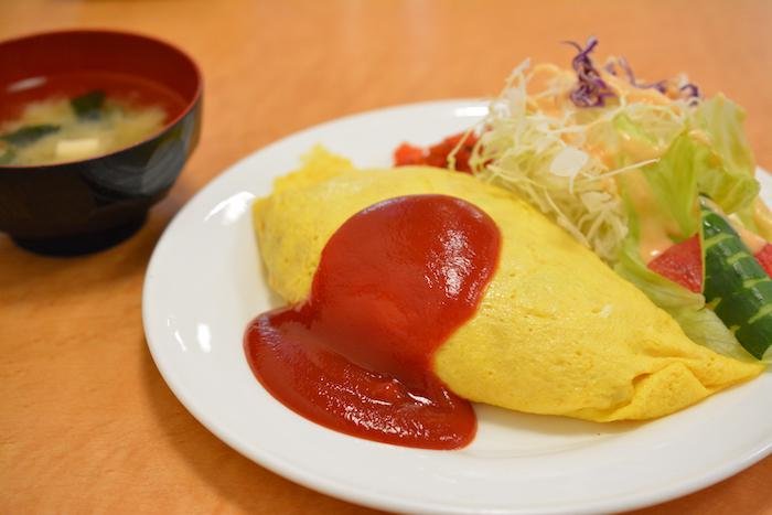 Omurice on a plate with salad next to a bowl of miso soup