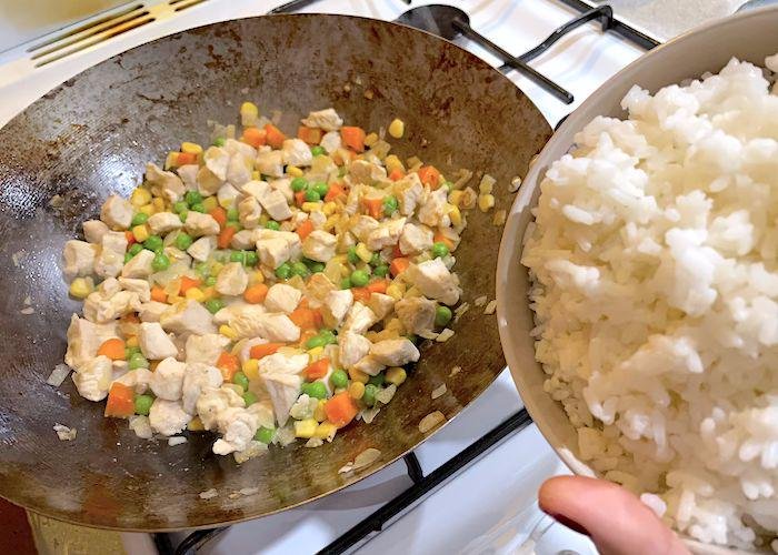 Adding the rice into the wok with vegetables for omurice