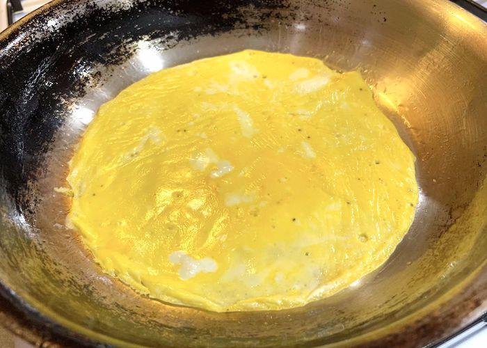 Omelette frying in frying pan on stovetop