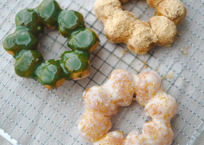 Matcha, yuzu, and kinako-flavored mochi donuts cooling on a wire rack