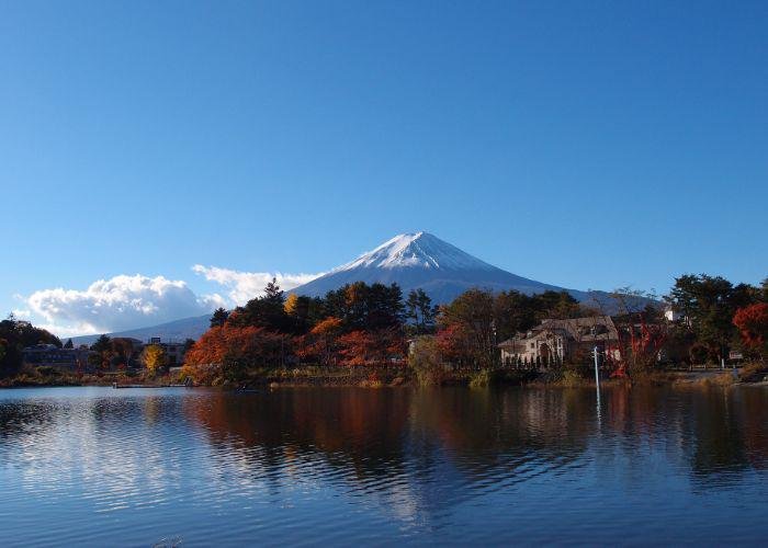 A photo of Mount Fuji from across Lake Kawaguchi, with red and orange trees in front
