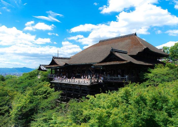The wooden veranda at Kiyomizu-dera temple overlooking a green valley and Kyoto city