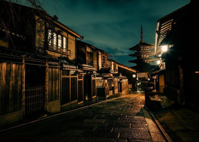 A street in Gion at night, with wooden buildings and a pagoda in the background